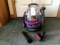 Front view of the Bissell SpotClean Pet Pro carpet cleaner with hose and attachments on the ground.