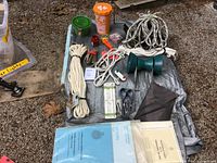 Photo showing various boating items including ropes, anchor, boating safety kit, and smaller accessories on tarpaulin.