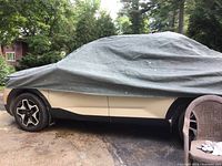 Side view showing grey car cover fitted over a convertible with exposed wheels, covering windows and body.