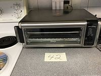 Ninja Foodie stainless steel digital air fryer oven on kitchen counter with control panel visible.