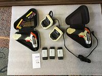 Full lot arranged on the blanket showing both drills in cases, two chargers, three batteries, and three bit sets.