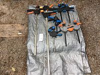 All 8 clamps laid out on a tarp showing 2 longer clamps and 6 shorter clamps in varying colors and designs