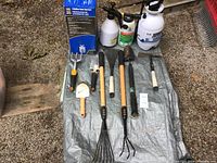 Overview of garden tools and spot sprayers arranged on tarp