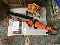 Hedge trimmer, blade guard, instruction manual and extension cord caddy shown together