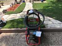 Front view of Homelite pressure washer with coiled hoses and wands.