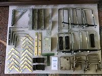 Overview of entire lot showing variety of metal brackets and U bolts arranged on a carpeted surface