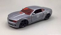 Front angle view of the metallic silver Chevrolet Camaro 1/32 scale Avengers Marvel diecast model, showing red tinted windows and black wheels, minor wear visible.