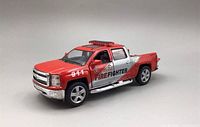 Red diecast model truck with firefighter decals and 911 on front fenders and side, front view showing chrome grille and details.