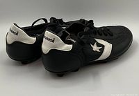 Side view showing black and white Converse cleats with logo and laces.