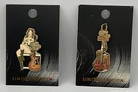Front of the two Hard Rock collector pins attached to black backing cards. Shows a 3D gold silhouette guitar pin and a 70s decade girl pin.