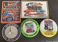 Photo of 5 vintage mini metal pins related to Mercedes-Benz and various car shows arranged on a white surface.