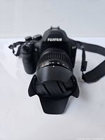 Front view showing Fujifilm branding, handgrip and lens with petal hood