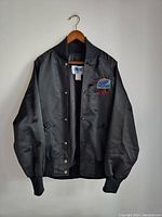 Front view of black satin vintage jacket showing button closure and ribbed cuffs/hem