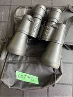 Binoculars placed on black carrying pouch with 'LOT #6' label visible.