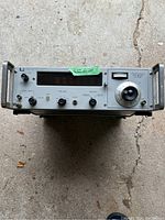 Front view of HP 5246L Frequency Counter showing control knobs, switches, nixie tube display window, and analog dial.