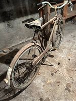 Full side view of an adult Raleigh bicycle showing frame, seat, tires, and handlebars; dusty, rusted, needs cleaning.