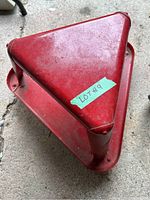 Top angled view of the red triangular work stool showing its flat red metal surface with some dirt and wear.