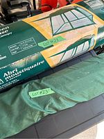 Boxed 12x12 foot screen house packaging showing product image and dimensions, taped with seller's lot number.