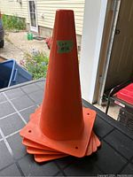 Stack of four bright orange safety cones with square bases and a tapered cone shape, each measuring 12 inches tall, placed on a table.