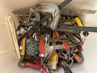 Overview of small tools including clamps, screwdrivers, pliers, saw, metal chain and various hand tools with visible rust and wear.
