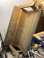 Full view of the wooden swing bench showing the slatted design of the seat and backrest, armrests, and weathered wood finish.