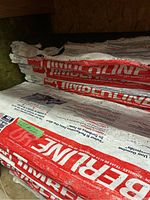 Photo showing red and white Timberline branded packaging on bundles of shingles stored in a garage.