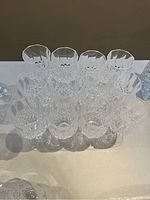 Top view of twelve crystal stemmed wine glasses arranged in rows, showing intricate cut-glass pattern on bowls.