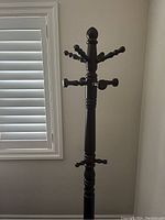 Full view of the wooden coat hanger stand showing its height and peg details from the front.