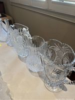 Side angled view of the group of crystal jugs showcasing their different shapes and cut patterns on a white table.