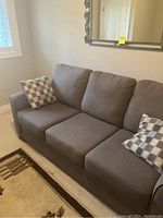 Shown from front-left angle with two checkered pillows on the couch and a carpet below.