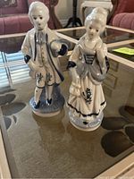 Front view of the porcelain man and woman figurines on a glass table.