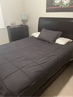 Queen size bed with dark brown wooden frame, headboard and footboard visible with bedding in place.