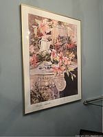 Framed Marilyn Siraudle print hung on a wall, showing full composition of flowers, cup, and decorative elements.