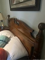 Photo of the solid wood queen size headboard showing curved top and rounded finials on each side.