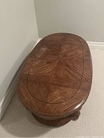 Top view of the oval wooden coffee table showing patterned wood surface with scratches.