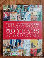 Front cover of the Playboy cartoon collection book with shrink wrap and retail price sticker.