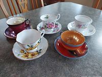 Top view of five vintage bone china tea cup and saucer sets on table showing colors and floral designs