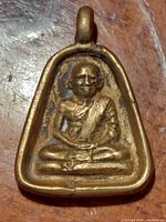 Front view of the cast brass Buddha pendant showing the seated Buddha figure.