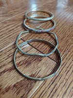 Four vintage silver and stone bangles on a wooden floor, showing various shapes and textures