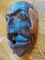 Front angled view of the wooden eagle transformation mask highlighting facial carving and wood grain