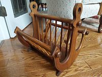 Side angle view showing the wooden anchor shape magazine holder with slatted magazine compartments and rounded details.