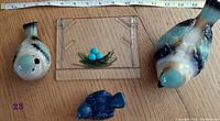 Ceramic birds of various sizes and a small square glass plate displayed with a ruler for scale