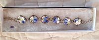 Full view of the ceramic bracelet with blue floral design laid out in box.