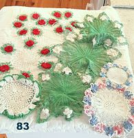 Full lot of intricately crocheted doilies showing various floral designs and colors arranged on a neutral surface.