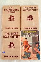 Top view of four Hardy Boys books showing front covers; three with beige covers and one with illustrated dust jacket.