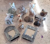 Overall view of the ten ceramic cat figurines in various poses and colors plus two pewter cat-themed frames, showcasing size and design