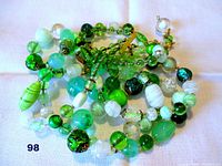 Close-up of various green and white beads of different shapes and sizes.