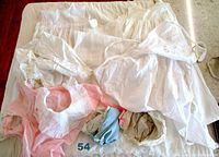 Full view of the vintage children's clothing laid out, showing white linens, pink pinafore, blue and beige shorts, and bonnets.