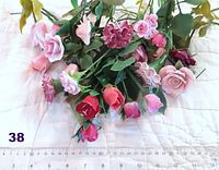 A bunch of assorted porcelain roses with stems in pink, red, and variegated colors laid flat with a ruler showing approximate lengths of about 30 cm. Some roses have minor chips on petals.