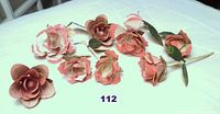 Seven wired metal roses laid out on a table, showing varying sizes and attached stems and leaves on some pieces.